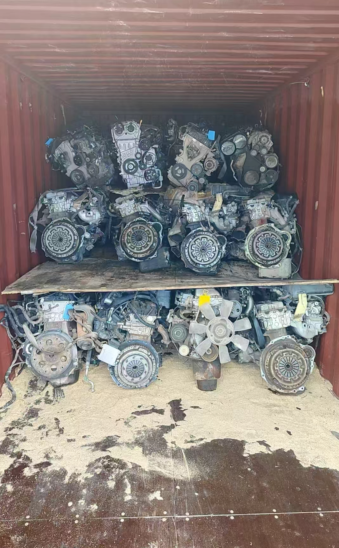 Used engines arranged on two tiers inside a red shipping container
