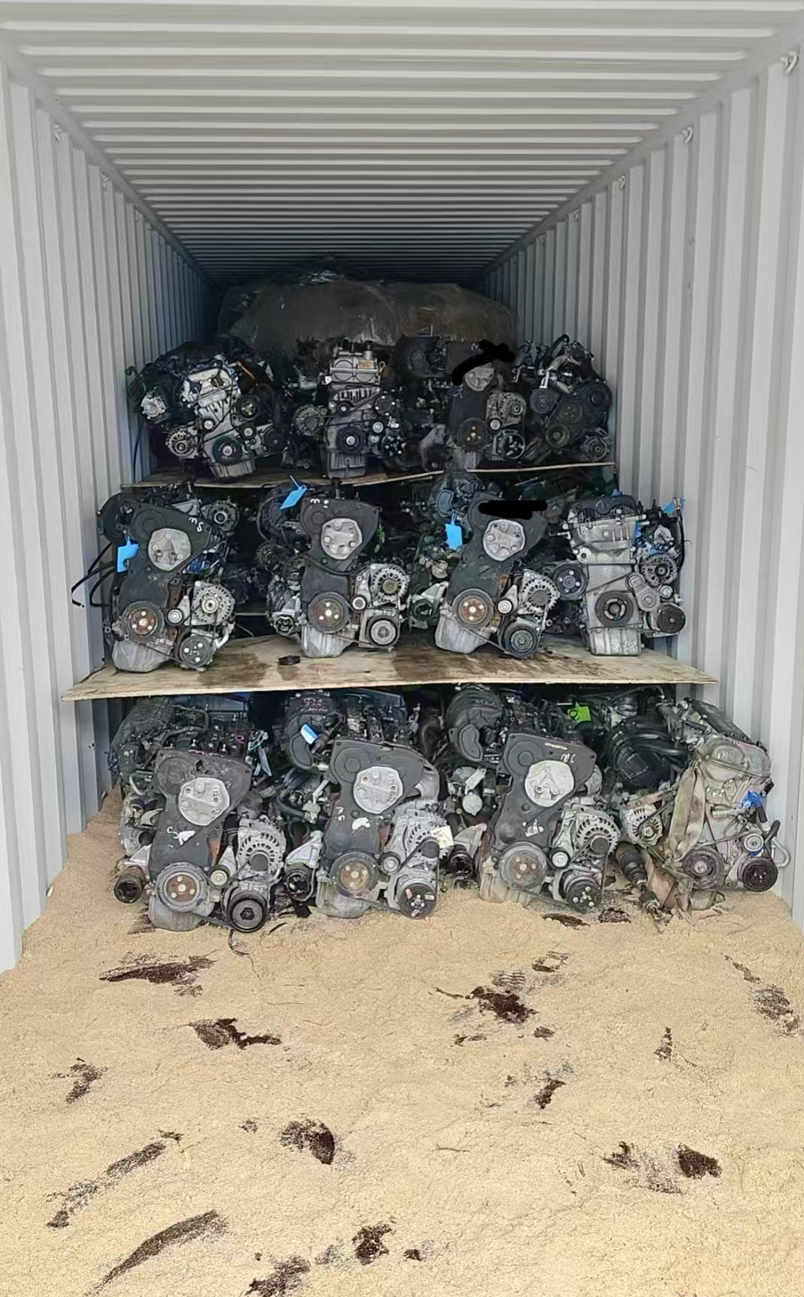 Tagged used engines arranged in rows inside a white shipping container