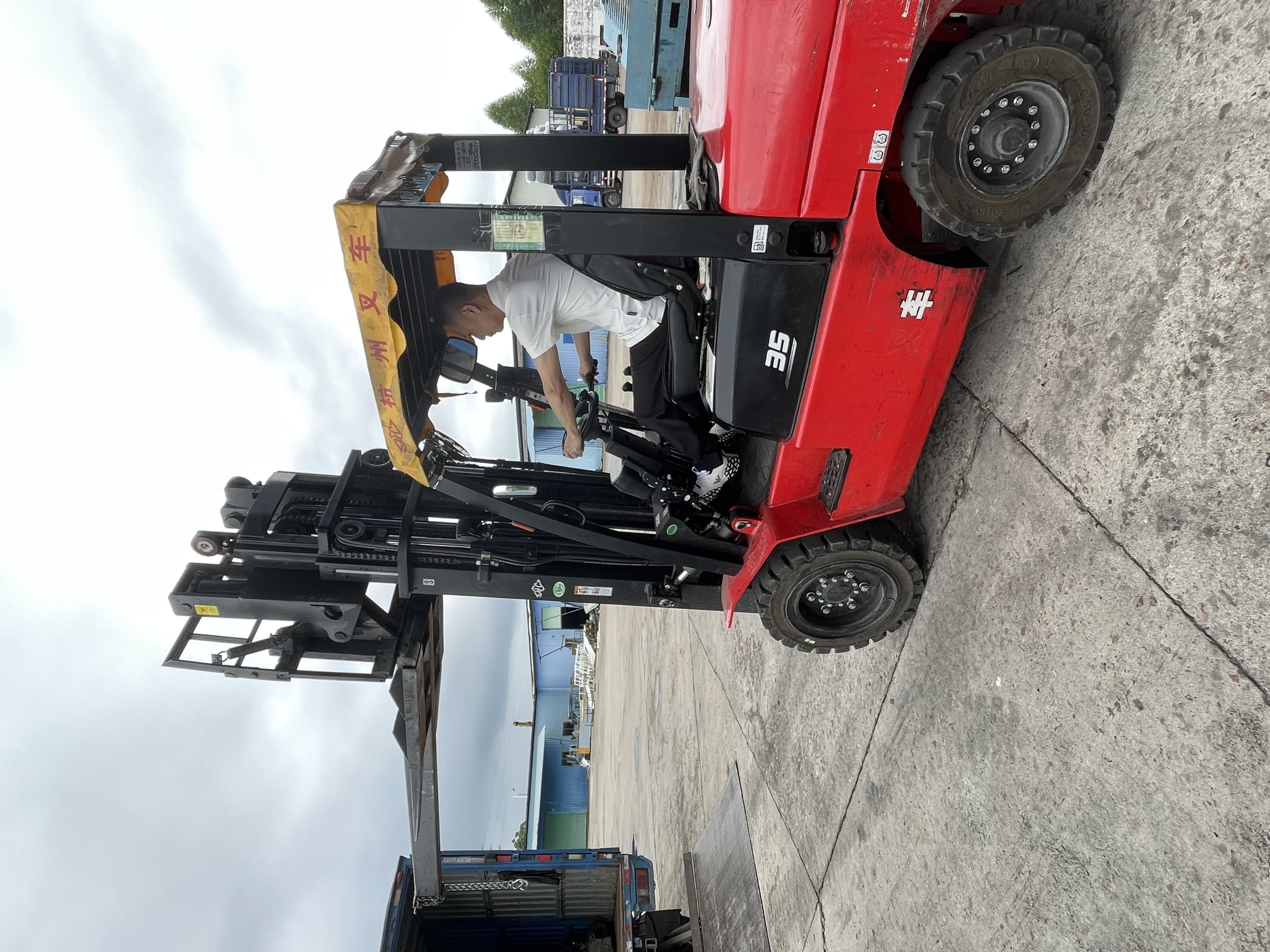 Forklift beside an open cargo truck at a loading yard