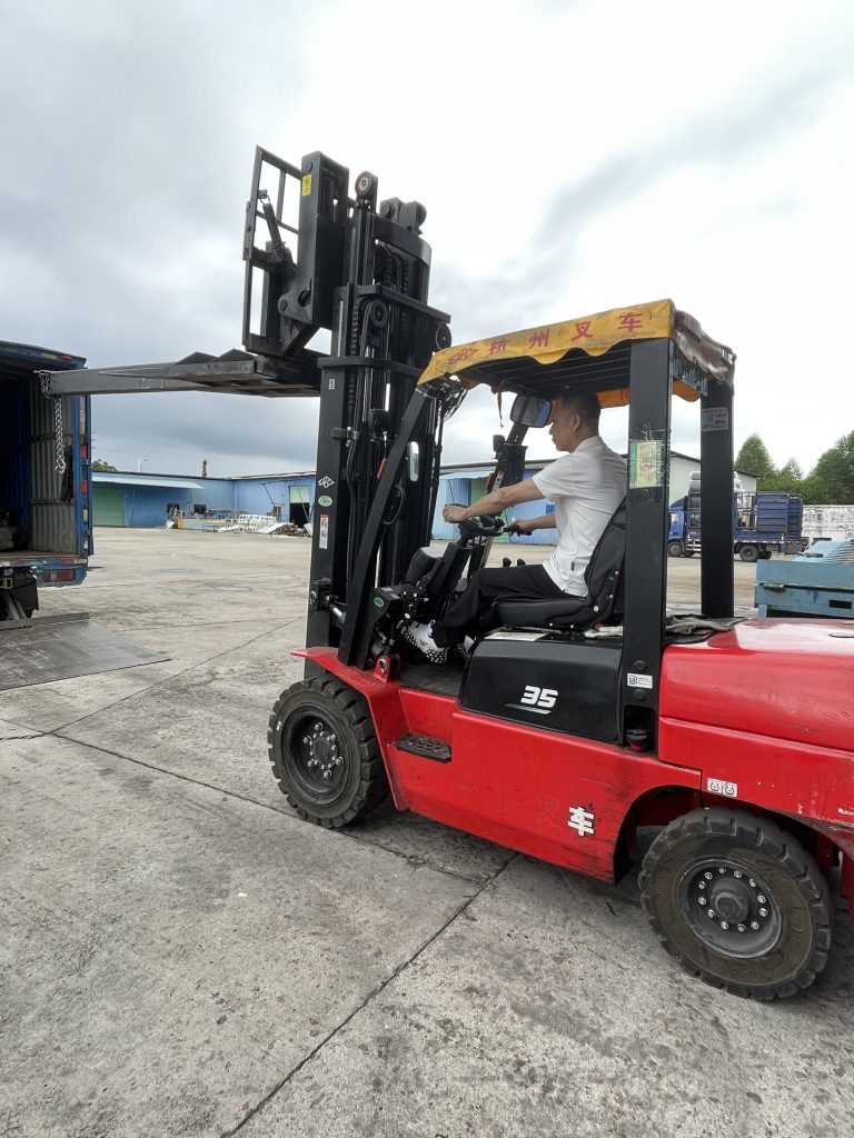 Forklift beside an open cargo truck at a loading yard